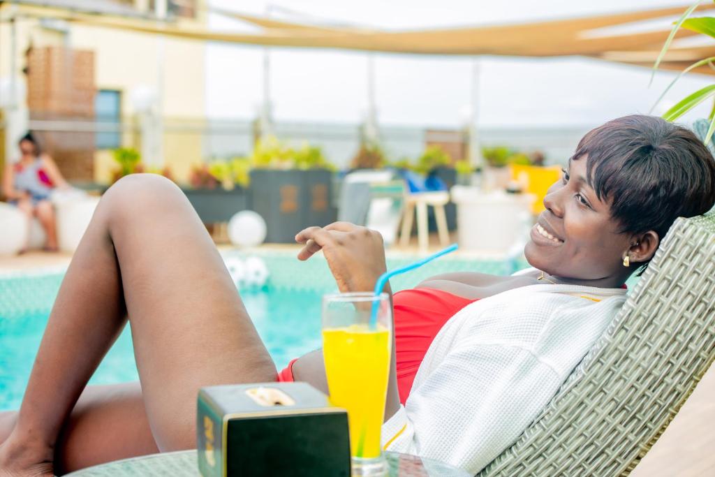 een vrouw in een stoel met een glas sinaasappelsap bij 520 hôtel & Résidence in Abidjan