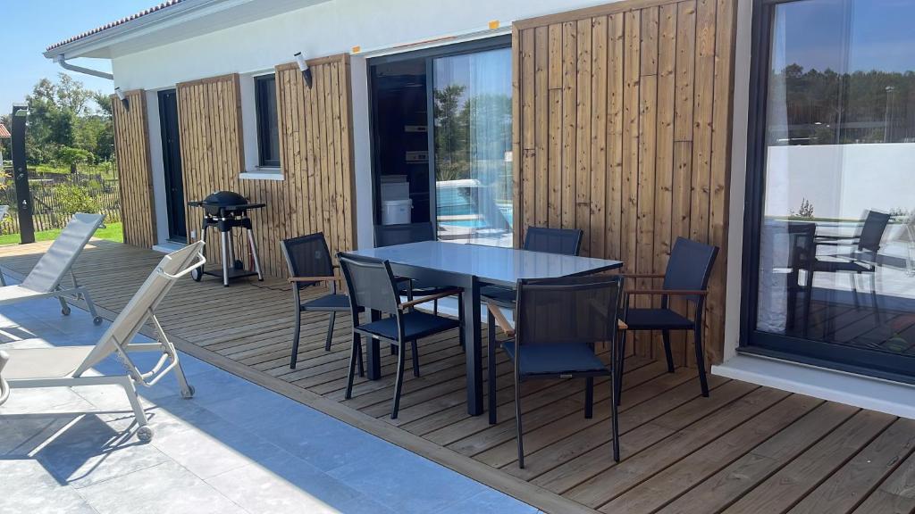 un patio avec une table et des chaises sur une terrasse dans l'établissement Villa Chrisaline, Centre Moliets, 3 chambres parentales, 10-15 personnes, équipements premium, à Moliets-et-Maa