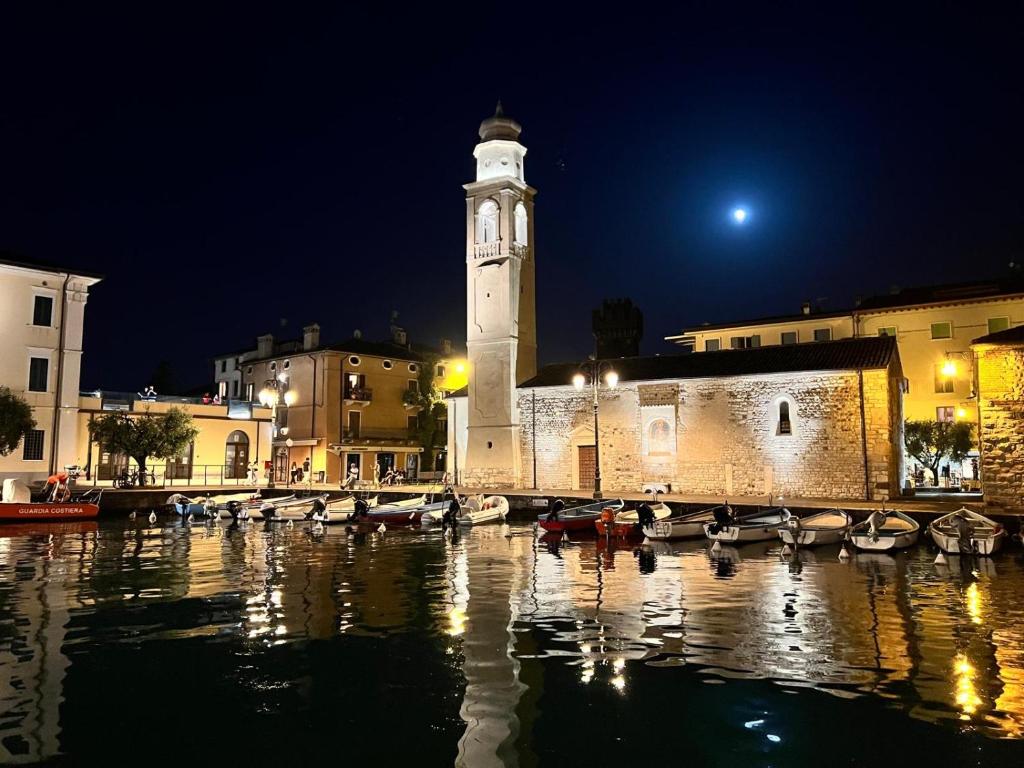 un edificio con torre dell'orologio con barche in acqua di LA CASA DI LAZISE a Lazise