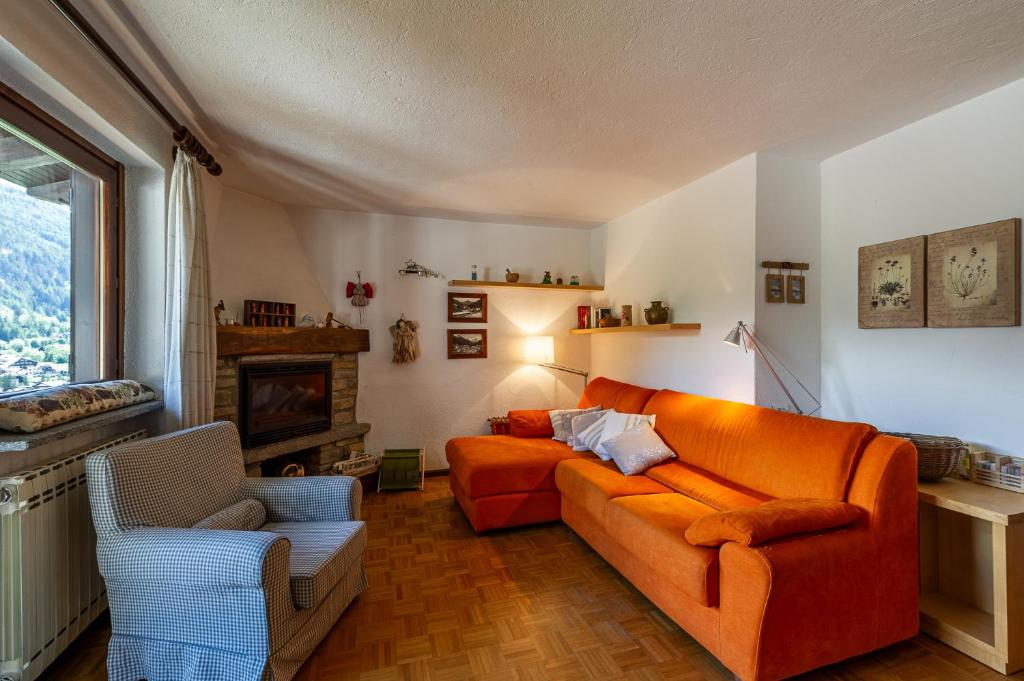 an orange couch in a living room with a fireplace at MAISON MOULIN - Relax e vista Montagna - LA THUILE 0107 in La Thuile