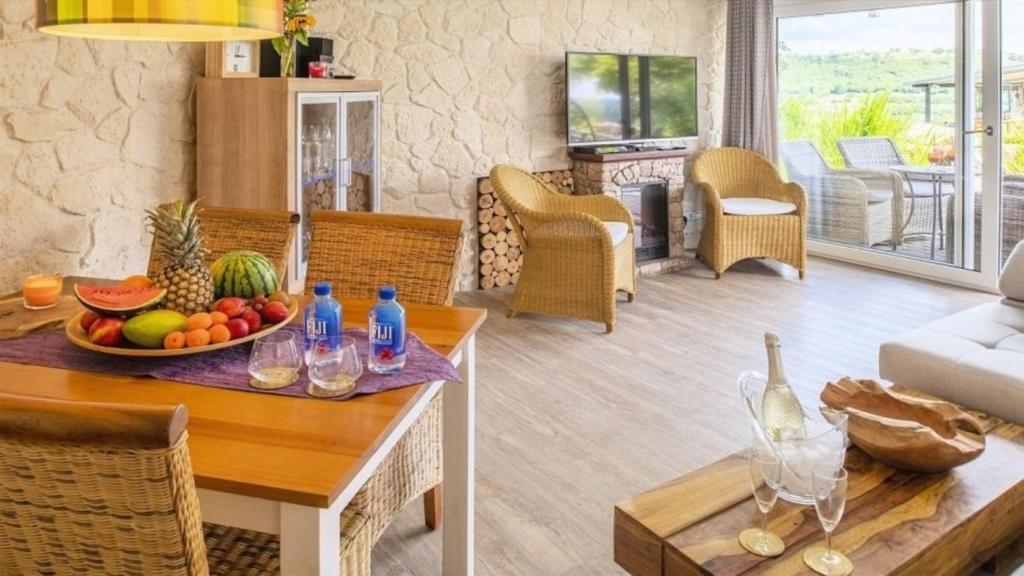a living room with a table with a bowl of fruit at Ferienwohnung Apartment Seeterrasse - im Maarberg Resort - in Schalkenmehren am See in Schalkenmehren