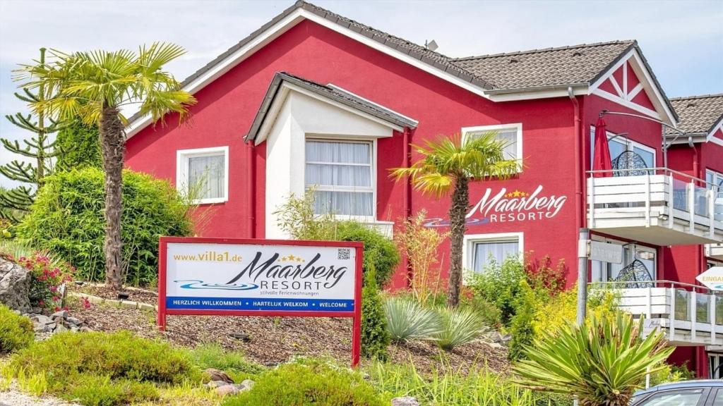 a red house with a sign in front of it at Ferienwohnung Studio Vulkanhöhe - im Maarberg Resort - in Schalkenmehren am See in Schalkenmehren