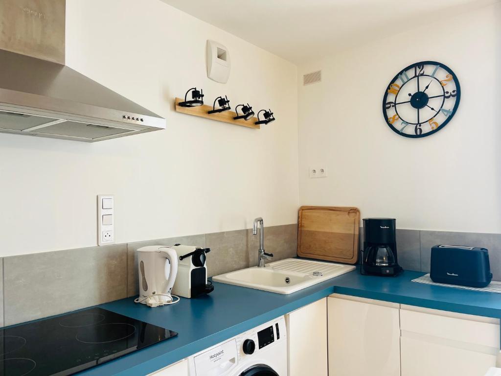 une cuisine avec un évier et une horloge murale dans l'établissement Market Appart 44m2 - 1 chambre - près du Marché, à La Rochelle