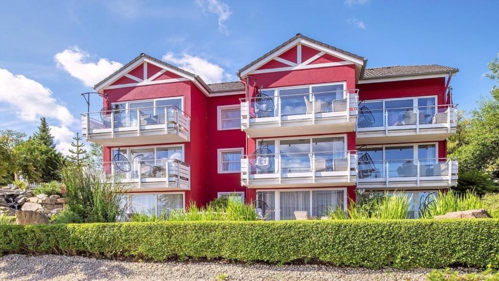 a red building with bushes in front of it at Ferienwohnung Maarpanorama in Schalkenmehren am See in Schalkenmehren