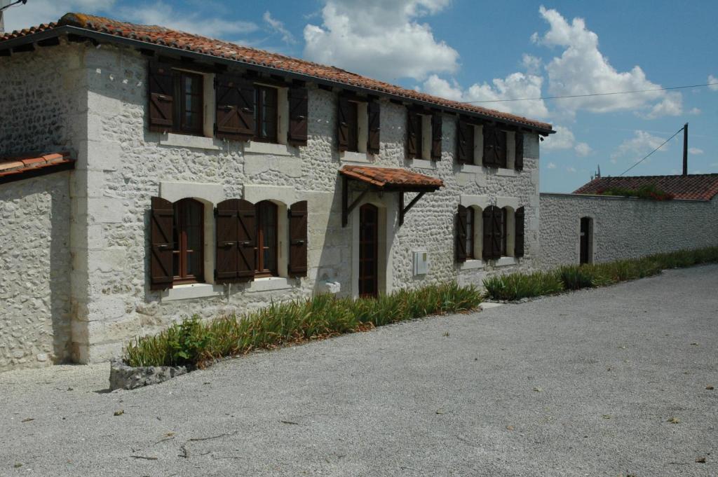 a white brick building with brown windows on it at Nandolle Farmhouse in Nanteuil-de-Bourzac