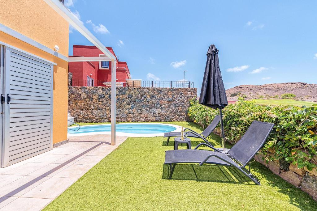 patio z parasolem i 2 krzesłami oraz basenem w obiekcie Vista Golf 12 by CanariasGetaway w mieście Maspalomas