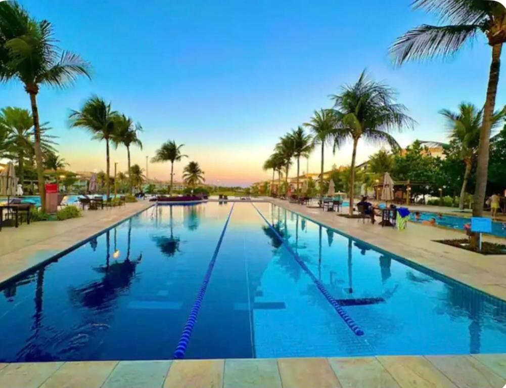 ein großer Swimmingpool mit Palmen in einem Resort in der Unterkunft Golf Ville Residence Resort, apartamento 3 suítes, 110m2, Porto das Dunas próx ao Beach Park in Aquiraz