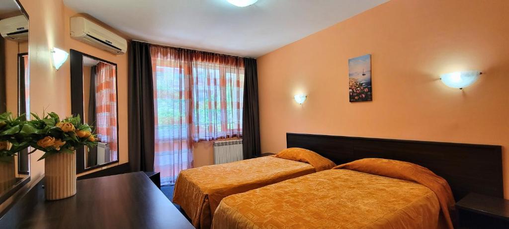 a bedroom with a bed and a table and a window at Hotel Bijou in Burgas