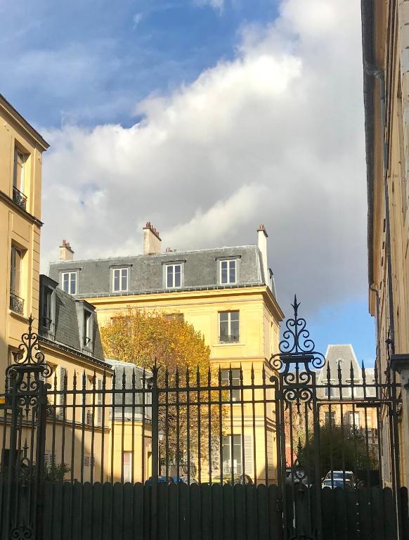 un bâtiment jaune derrière une clôture noire dans l'établissement Au coeur de Versailles, à Versailles