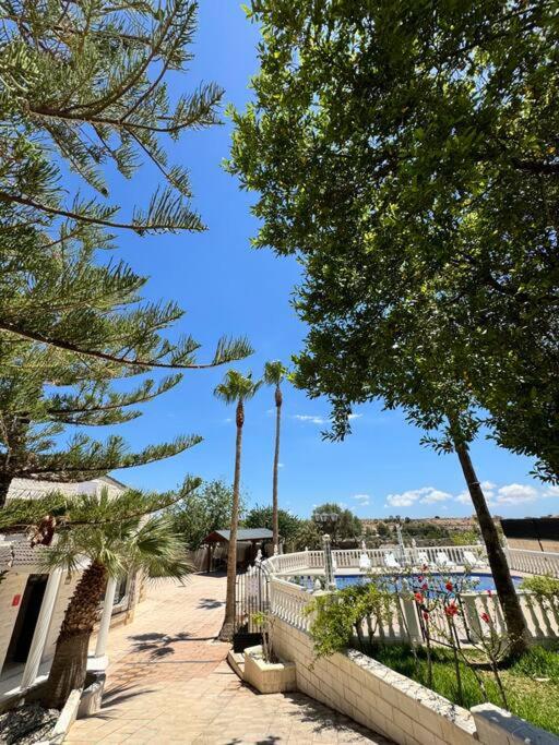 a park with palm trees and a white fence at Villa con piscina privada in Alicante