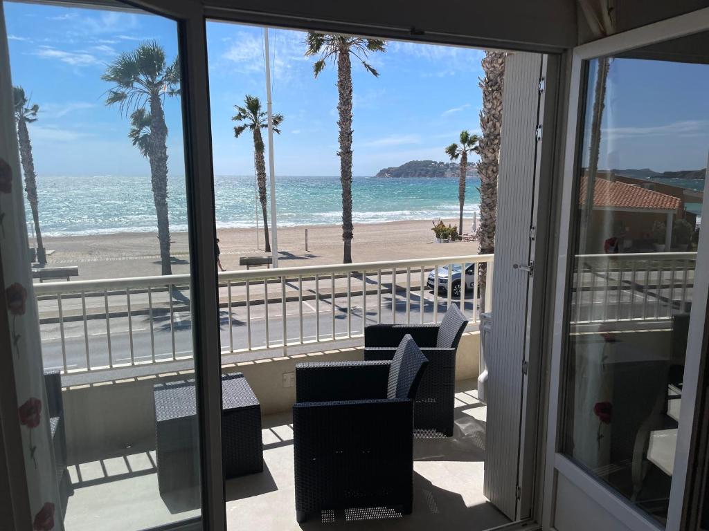 een balkon met uitzicht op het strand en de palmbomen bij la plage in Six-Fours-les-Plages