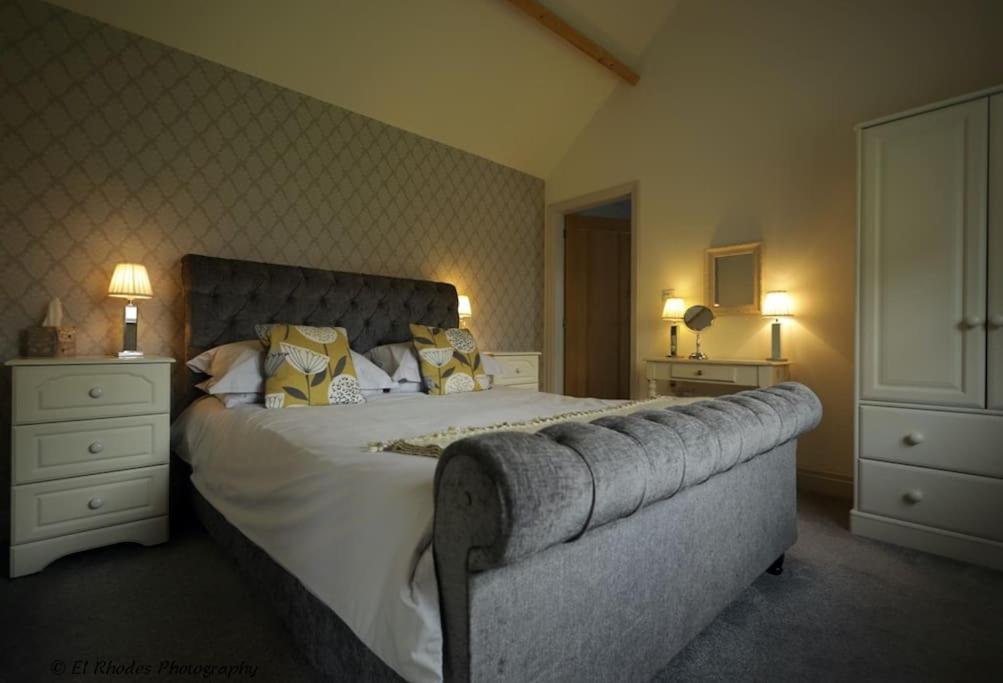 a bedroom with a large bed and two night stands at Pretty Garden Cottage in Tollerton