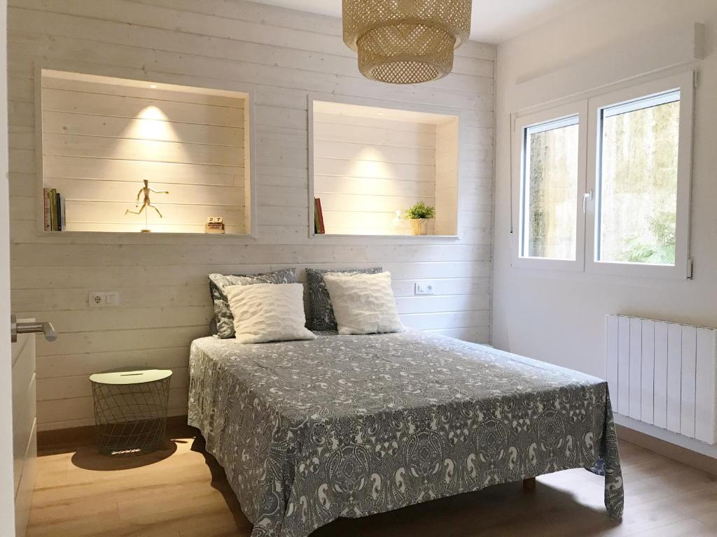 a bedroom with a bed and two windows at Coniferas in Santander