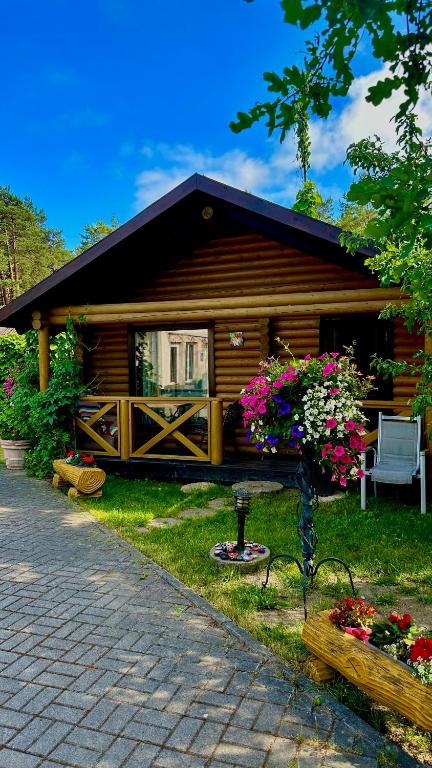 a cabin with a bench and flowers in front of it at Audrones sodyba in Šventoji