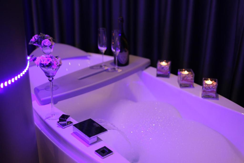Bubble-filled whirlpool tub with champagne bottle, two wine glasses, lit candles and LED strip lighting on dark purple wall at City Palace Hotel in Ohrid