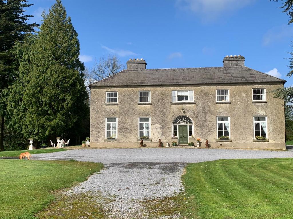 a large brick house with a dog in front of it at Lisglassock House in Longford