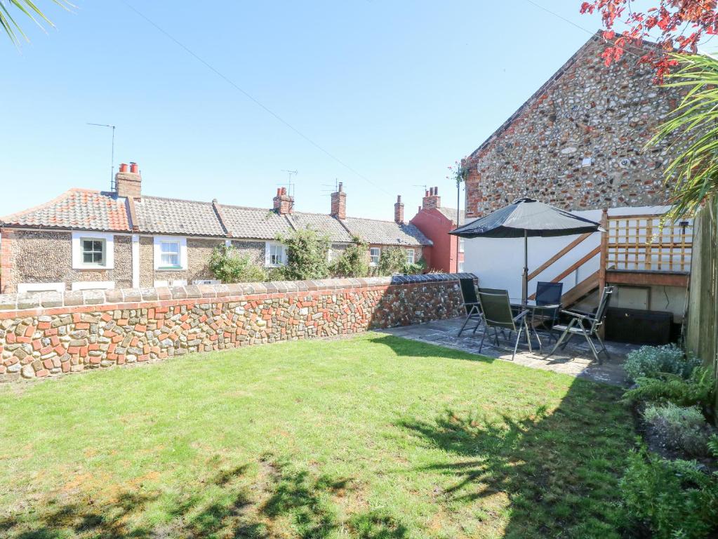 a backyard with a stone wall and an umbrella at Crab Corner in Wells next the Sea
