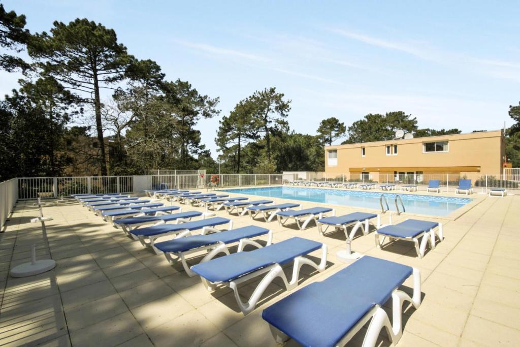 - une piscine bordée de chaises longues bleues dans l'établissement Résidence Les Grands Pins - maeva Home - Appartement 2 Pièces 5 Personnes - Confort MAE-1502, à Maubuisson