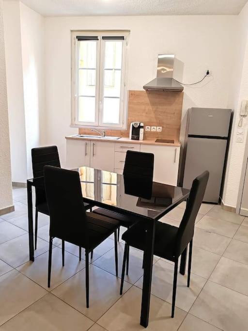 une cuisine avec une table en verre et des chaises noires dans l'établissement Le Centre du Monde, à Perpignan