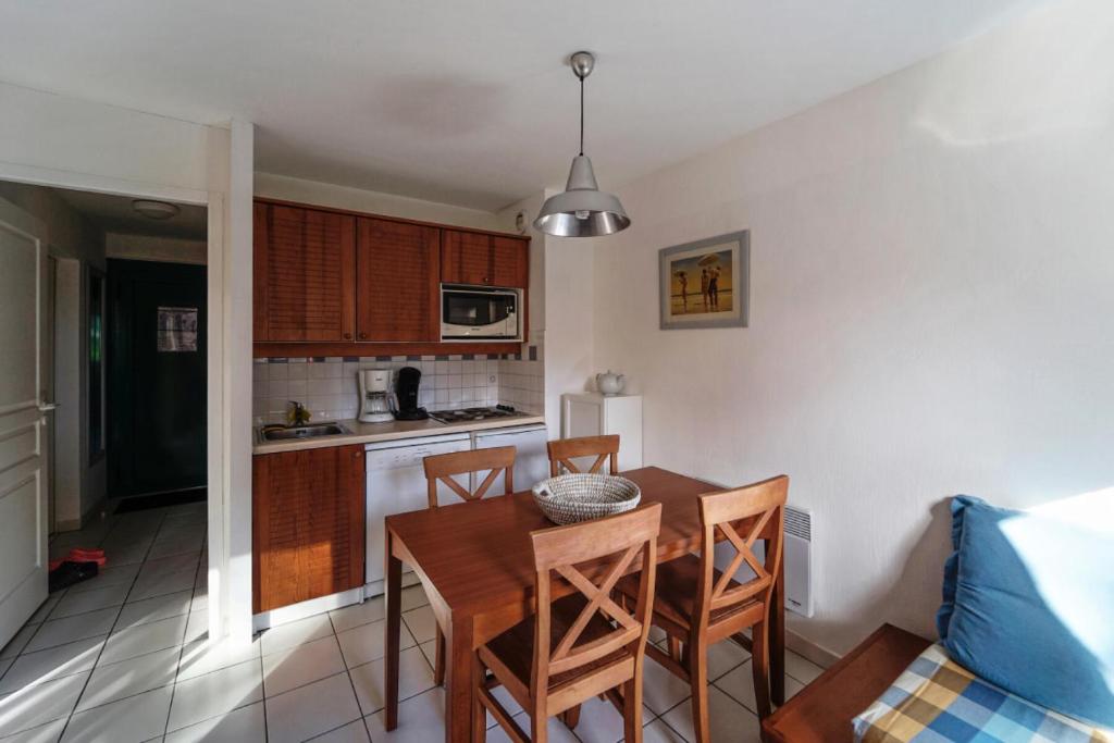 une cuisine et une salle à manger avec une table et des chaises dans l'établissement Résidence Les Grands Pins - maeva Home - Appartement 2 pièces 4 personnes Sélection MAE-1805, à Maubuisson