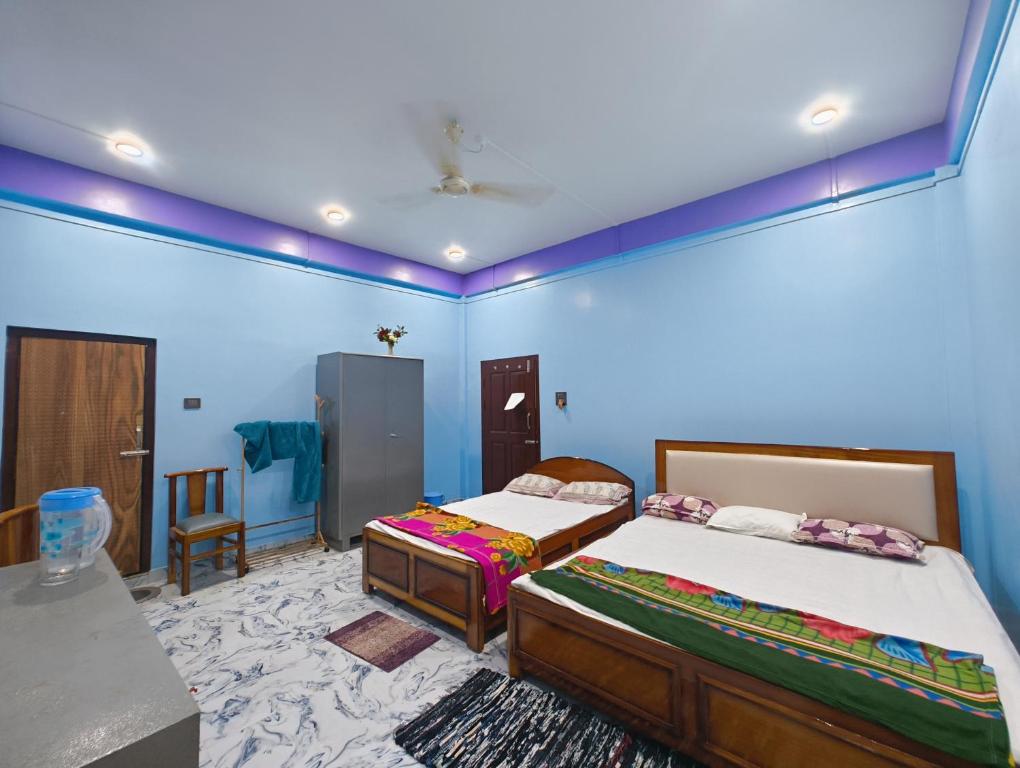 two beds in a room with blue walls at RG Homestay in Sivasagar