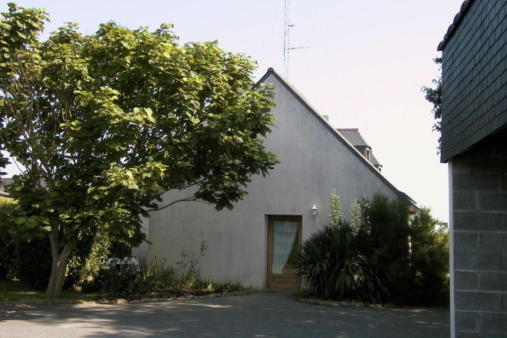 un bâtiment blanc avec un arbre devant lui dans l'établissement Petite maison près de la mer à Saint-Cast-le-Guildo, à Saint-Cast-le-Guildo