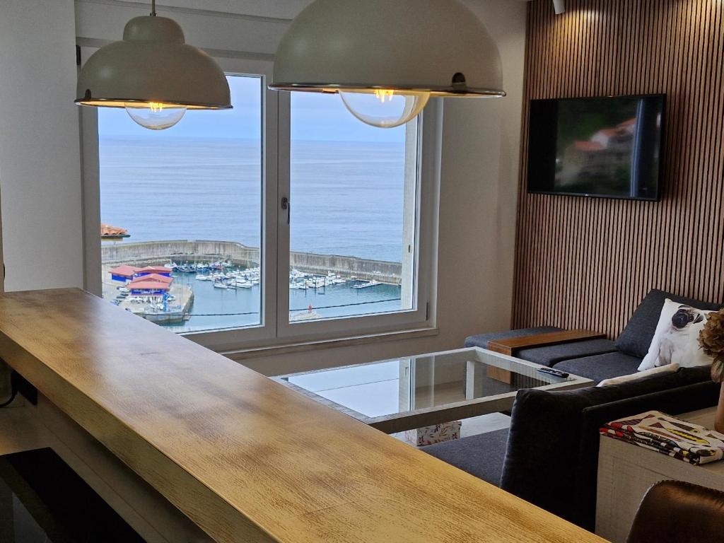 a living room with a large window with a view of a harbor at Casa Laurentina Lastres in Lastres