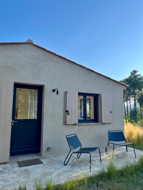 Deux chaises assises à l'extérieur d'un bâtiment avec une porte dans l'établissement Les Plaines, à La Môle