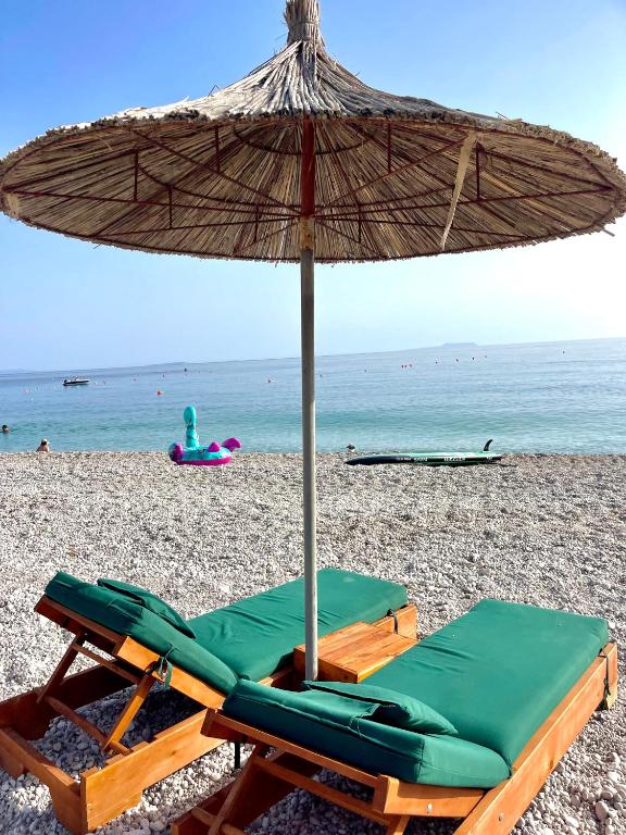 a beach chair with an umbrella on a beach at Chalet Ambel in Dhërmi