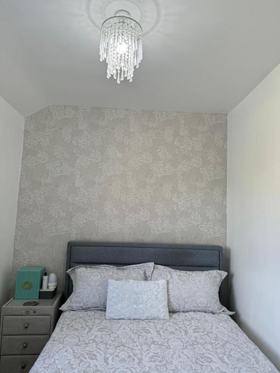 1 dormitorio con 1 cama con lámpara de araña encima en Home away home, en Great Barr