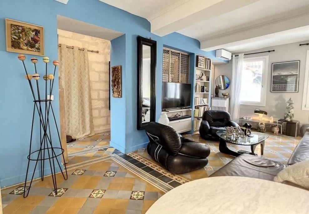 un salon avec des murs bleus et des chaises en cuir noir dans l'établissement T3 centre historique, 90m2, clim, terrasse, 4 pers, à Avignon