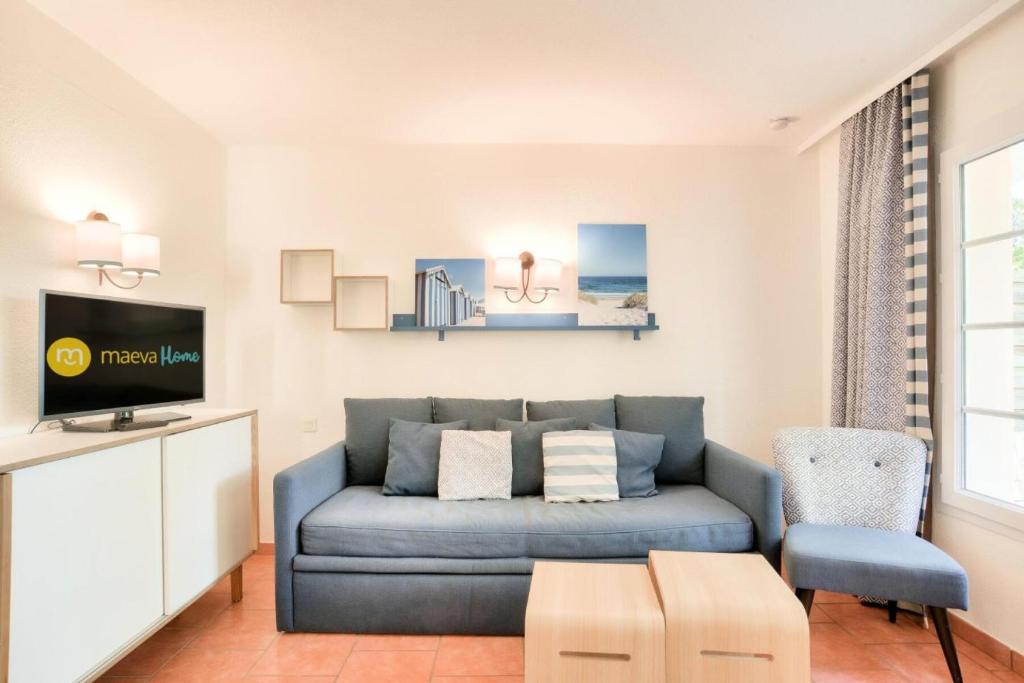 un salon avec un canapé bleu et une télévision dans l'établissement Les maisons de Moliets - maeva Home - Maison 3 pièces 6 personnes - Prestige MAE-2154, à Moliets-et-Maa