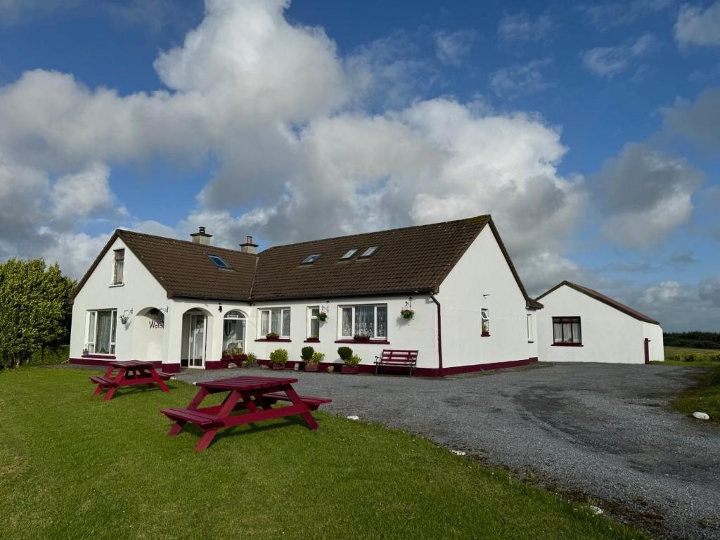 a white house with two picnic tables in front of it at Puffin rooms in Lisdoonvarna