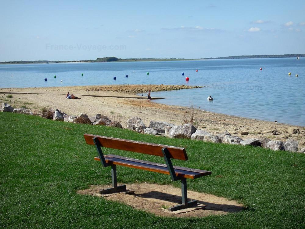 un banc assis sur l'herbe à côté d'une plage dans l'établissement ginalia cottage, à Éclaron
