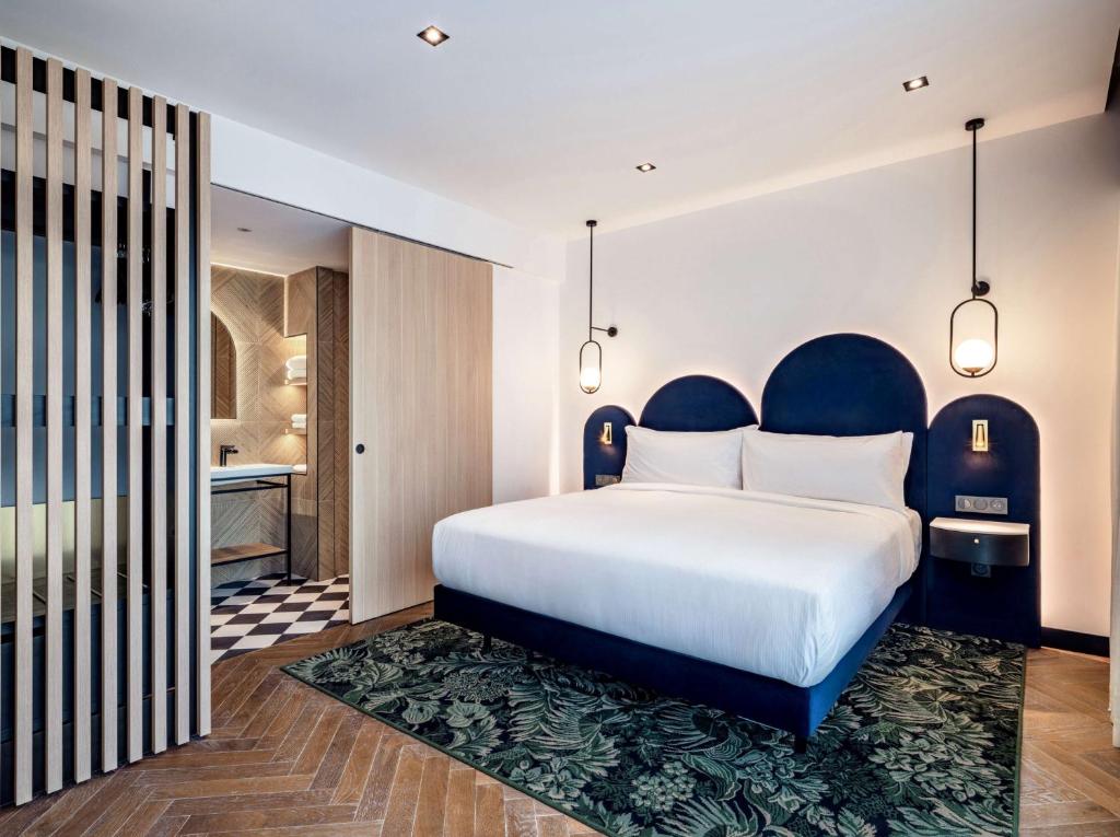 a bedroom with a large bed and a bathroom at Doubletree By Hilton Nice Centre Iconic in Nice