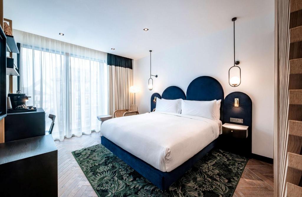 a bedroom with a large bed and a large window at Doubletree By Hilton Nice Centre Iconic in Nice