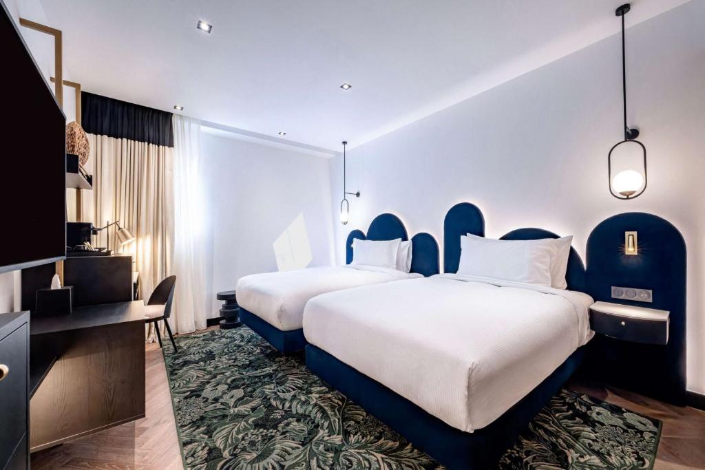 a hotel room with two beds and a tv at Doubletree By Hilton Nice Centre Iconic in Nice