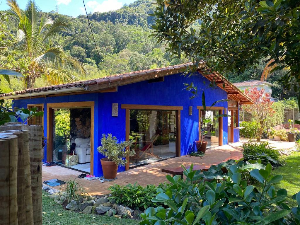 ein blaues Haus mitten in einem Garten in der Unterkunft Vila dos Tangarás, Casa 2 Boutique Riacho - 30m do mar in Toque Toque Grande