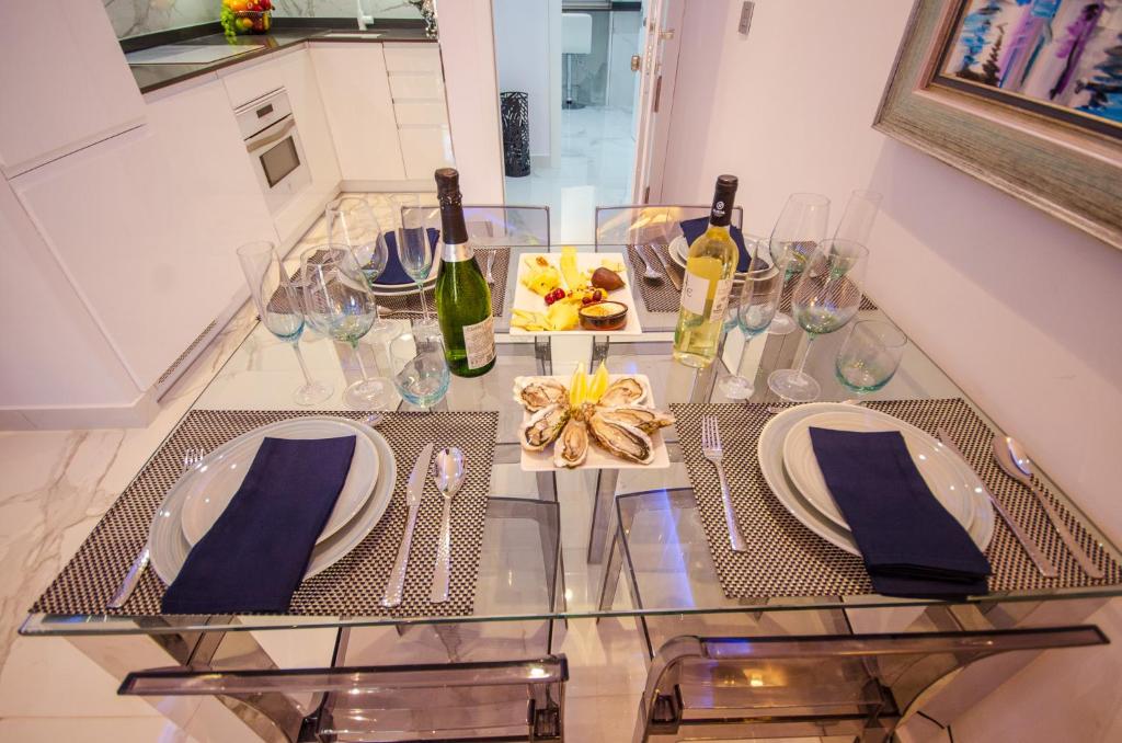 une table en verre avec deux assiettes et des bouteilles de vin dans l'établissement OASIS - PALM Old Town, à Benidorm