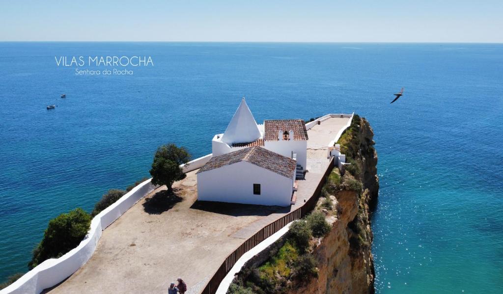 eine kleine weiße Kapelle auf einer Klippe neben dem Meer in der Unterkunft Marrocha II in Lagoa