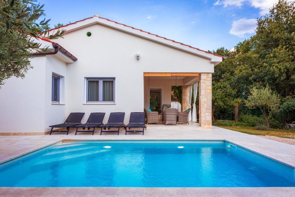a villa with a swimming pool in front of a house at Villa Nevera in Omišalj