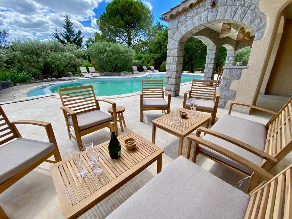 ルオムにあるMaison pour 12p, piscine à débordement chauffée d'avril à octobre inclusのスイミングプールの隣にパティオ(椅子、テーブル付)