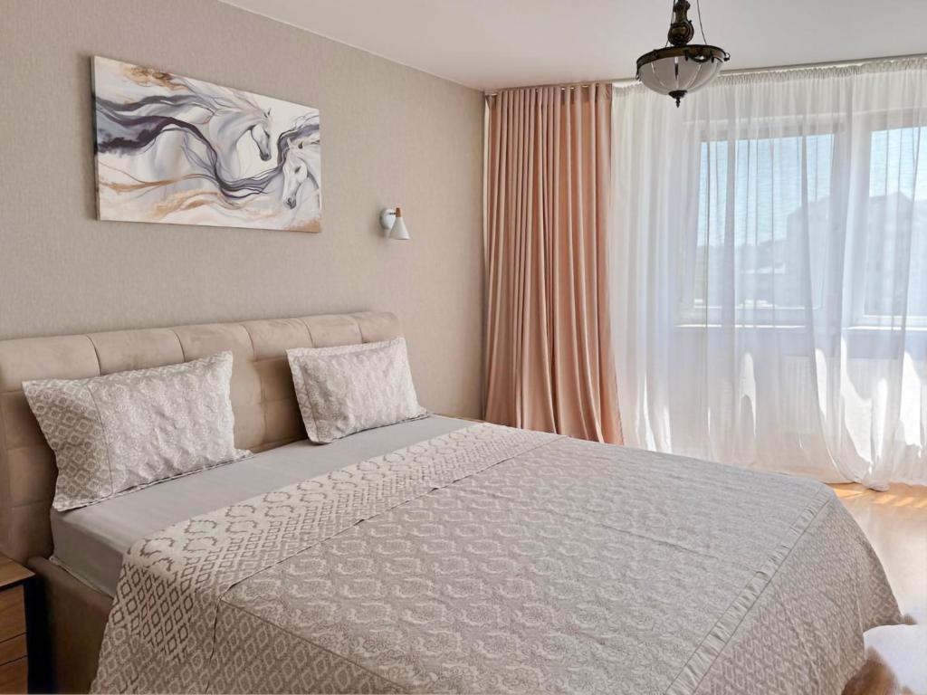 a bedroom with a bed and a large window at Charming,lovely and central with park view in Chişinău