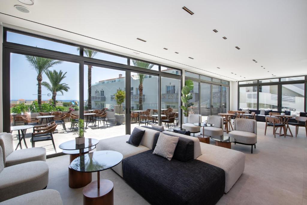 a living room with a couch and tables and windows at Selini Suites & Waterpark in Kolymvari