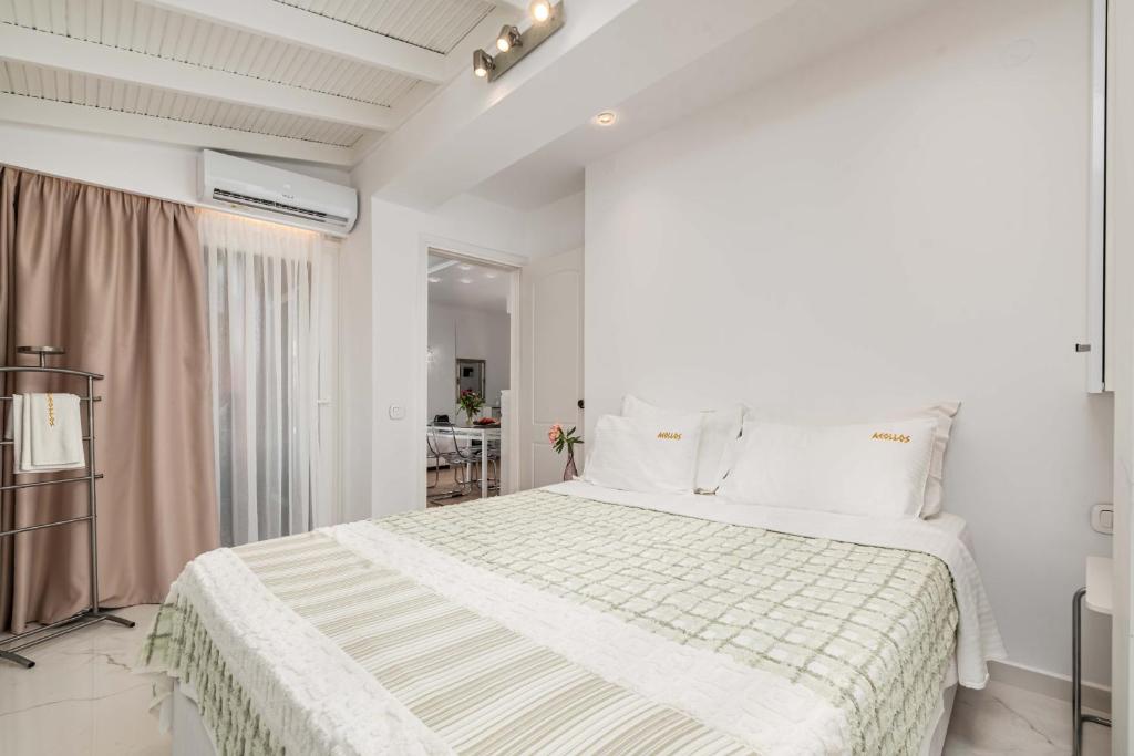 a white bedroom with a bed and a window at Hotel Aeollos in Pefkochori