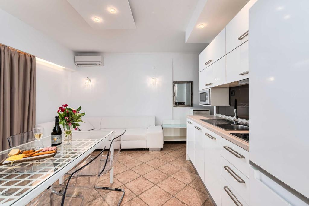 a white kitchen with a table and a couch at Hotel Aeollos in Pefkochori