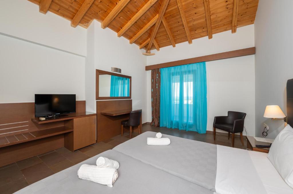 a bedroom with a bed and a desk and a television at Aktaion Resort in Gythio