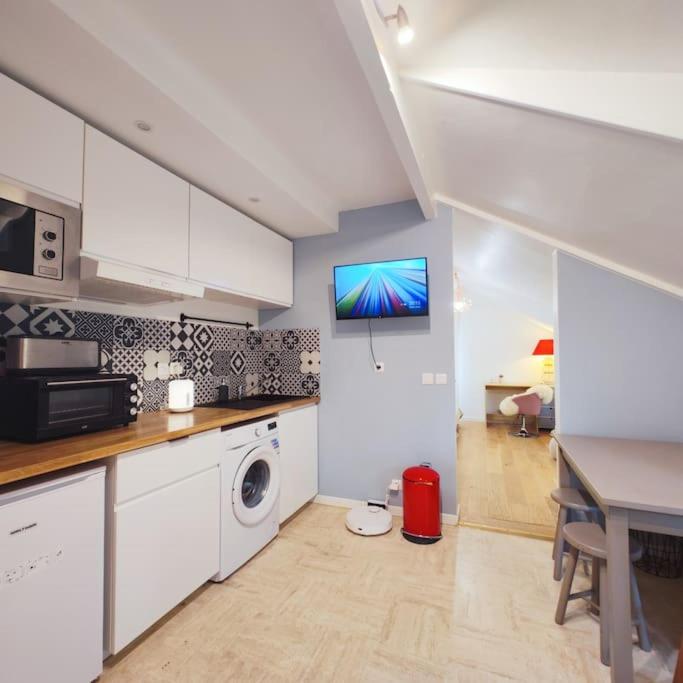 une cuisine avec un lave-linge et une télévision murale dans l'établissement un appartement individuel dans une maison proche de Paris avec un accès facile aux transports en commun, au Plessis-Robinson