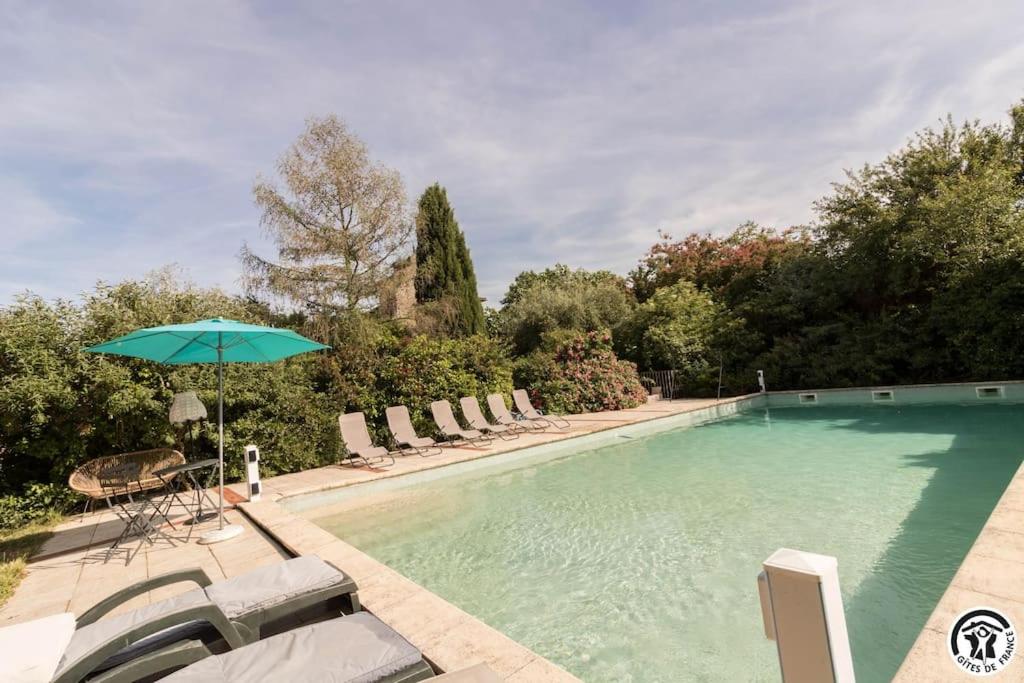 a swimming pool with chairs and an umbrella at Domaine d'en serres, 15th century castle in Saint-Marcel-Paulel