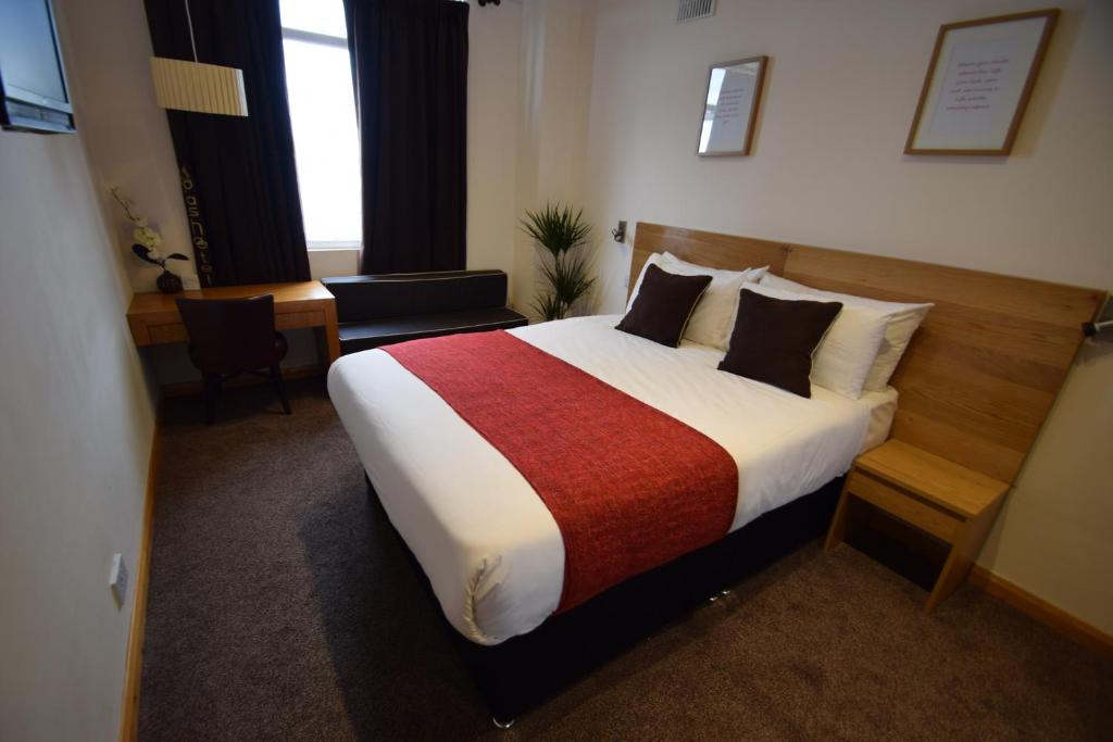 a bedroom with a large bed with a red blanket at Pasha Hotel - 3* Boutique Hotel in London